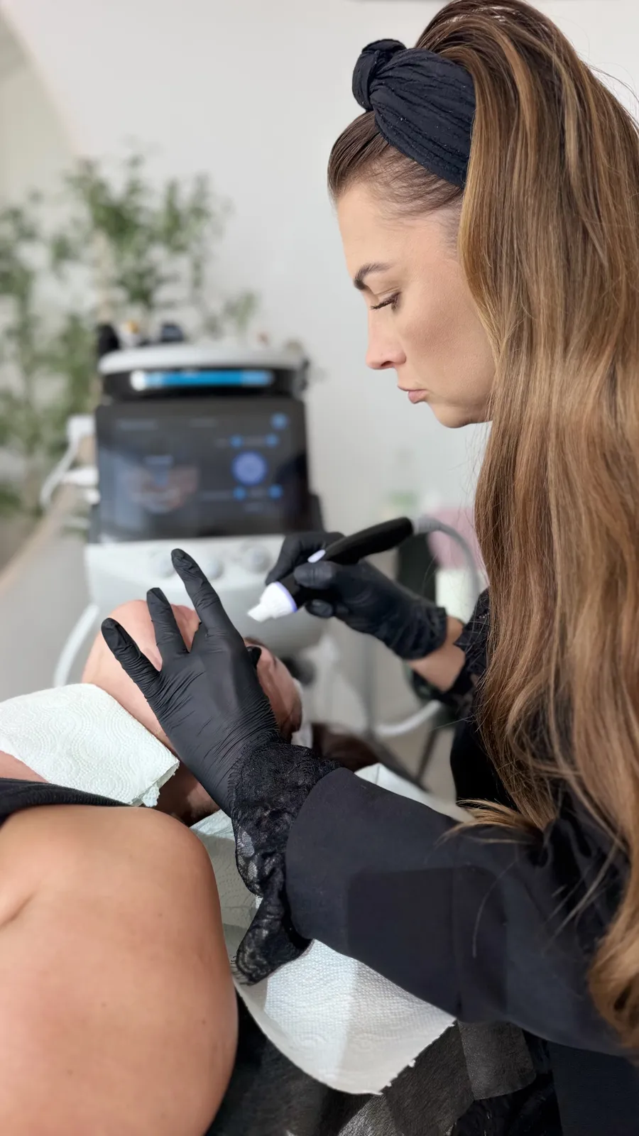 Kobieta z dwoma certyfikatami szkolenia obok kombajnu kosmetycznego na statywie, w tle złote logo SUNSPA Health and Beauty